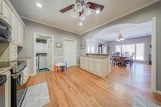 kitchen featuring ceiling fan, electric range oven, light wood-type flooring, washing machine and clothes dryer, and arched walkways