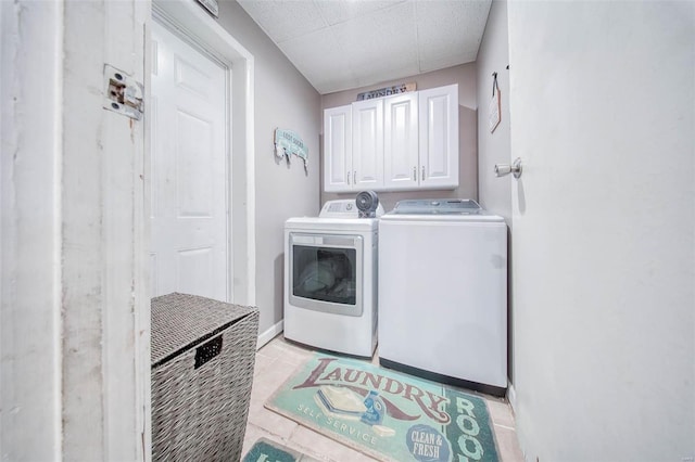 clothes washing area with independent washer and dryer, cabinet space, light tile patterned floors, and baseboards