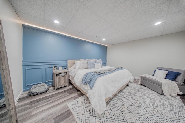 bedroom featuring light wood-style flooring, recessed lighting, a paneled ceiling, and baseboards