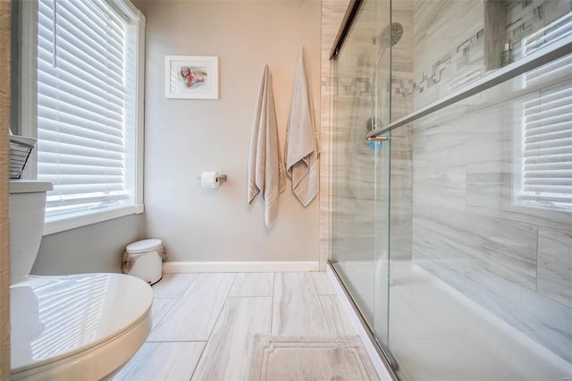 bathroom featuring a stall shower, toilet, and baseboards