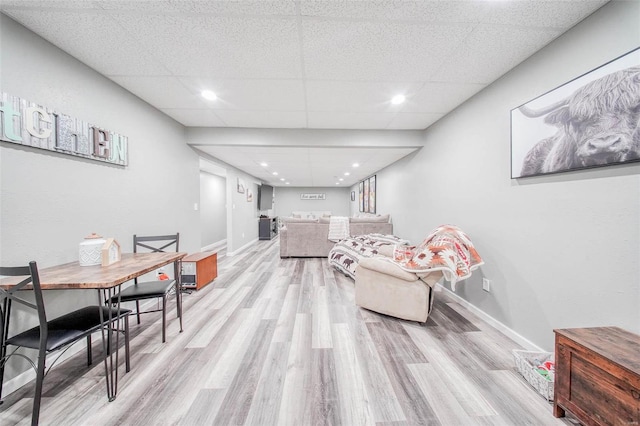 living room with light wood-style floors, baseboards, and a paneled ceiling