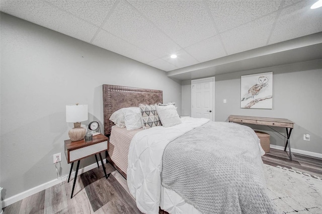 bedroom featuring wood finished floors, baseboards, recessed lighting, and a paneled ceiling