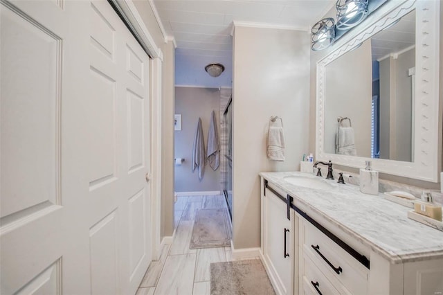 bathroom featuring vanity, baseboards, crown molding, and a shower with shower door