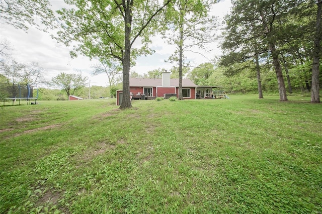 view of green lawn with a trampoline and an outdoor structure