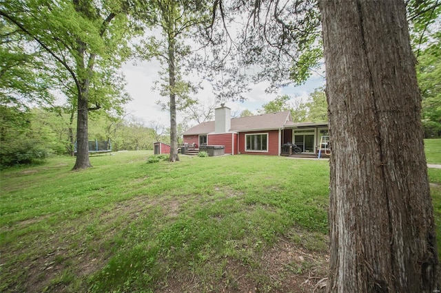 view of green lawn with a patio area, a trampoline, and a shed