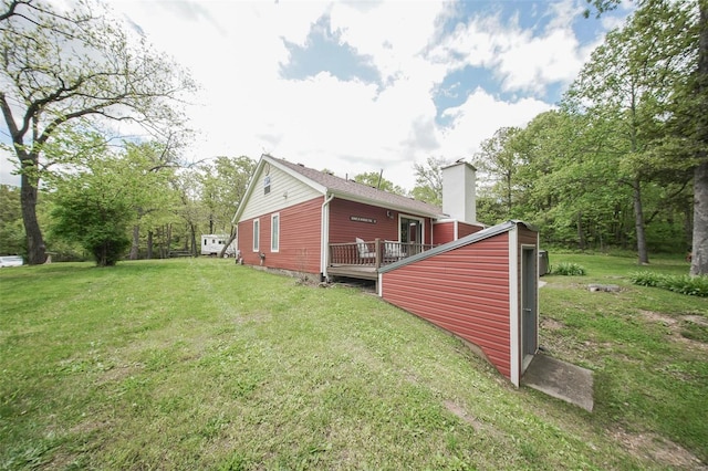 view of side of home featuring a chimney, a lawn, and a deck
