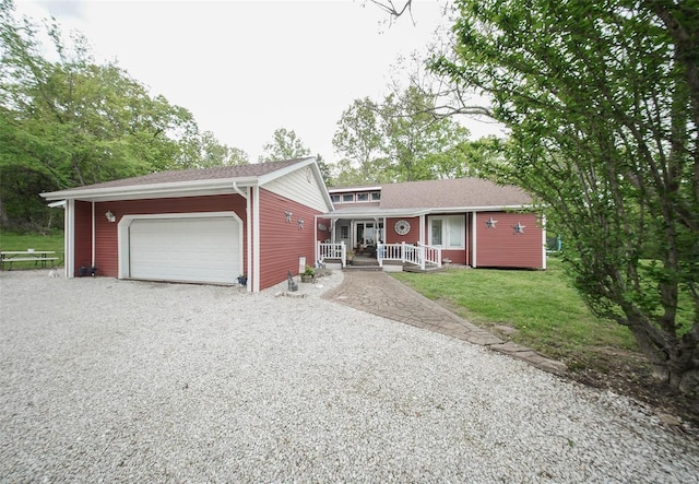 tri-level home featuring covered porch, driveway, a garage, and a front yard