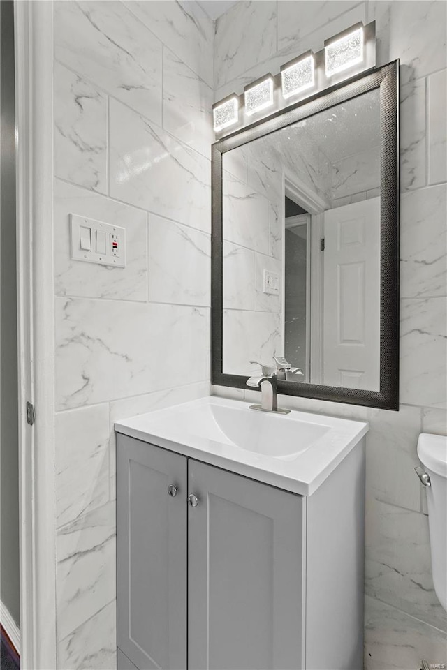 bathroom featuring tile walls, toilet, and vanity