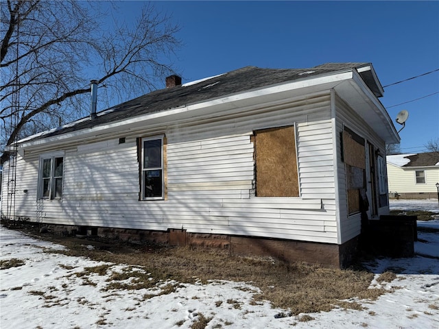 snow covered property featuring a garage and a chimney