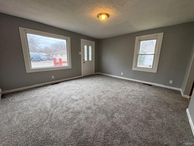 empty room with carpet floors and a textured ceiling