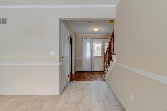 foyer entrance with stairs, ornamental molding, light carpet, and visible vents