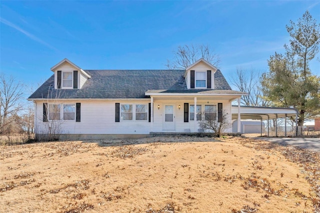 cape cod house with covered porch, driveway, and a detached carport