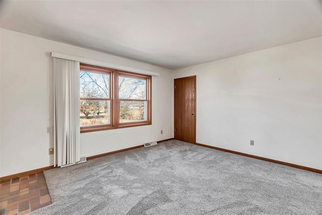 spare room featuring baseboards, visible vents, and carpet flooring