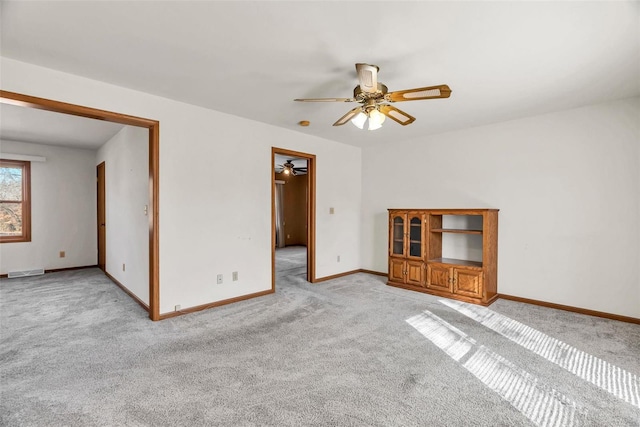 unfurnished room featuring ceiling fan, light colored carpet, visible vents, and baseboards