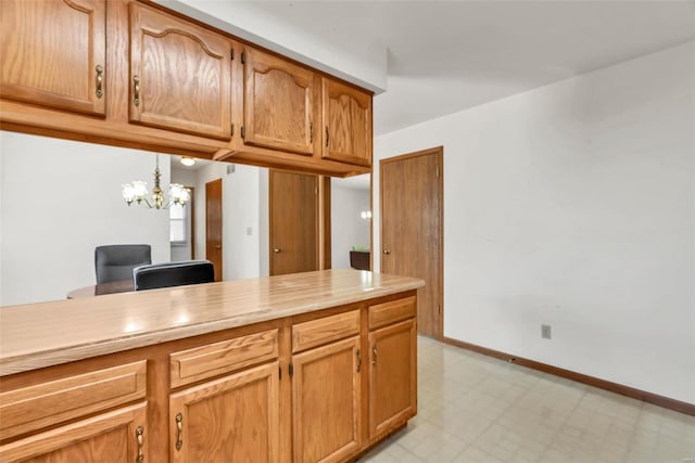 kitchen with baseboards, light countertops, light floors, decorative light fixtures, and an inviting chandelier