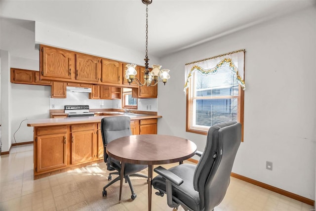 kitchen featuring under cabinet range hood, range with electric cooktop, hanging light fixtures, light countertops, and light floors