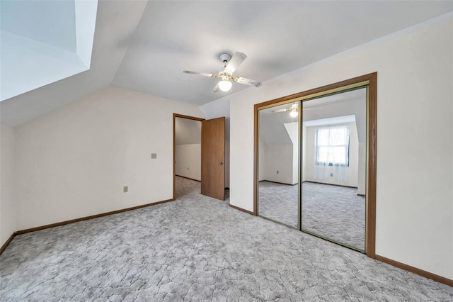 interior space with light carpet, ceiling fan, vaulted ceiling, and baseboards