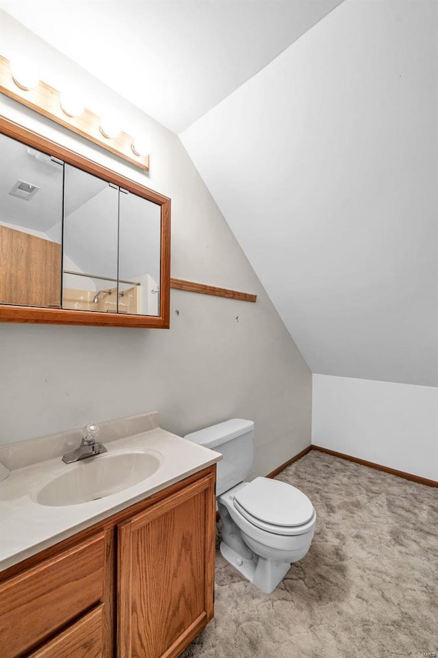 bathroom featuring baseboards, vaulted ceiling, vanity, and toilet