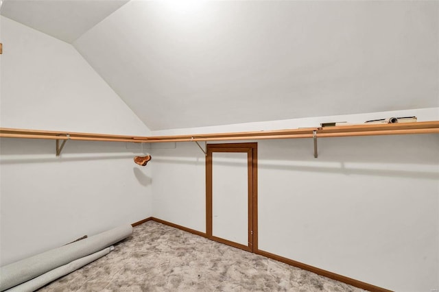 spacious closet with vaulted ceiling and light colored carpet