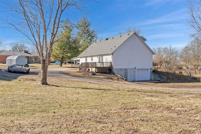 back of house featuring an attached garage, a lawn, and a wooden deck