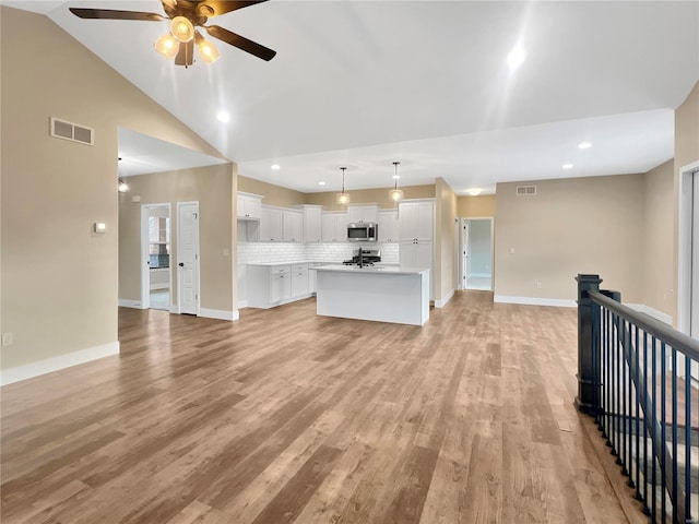 unfurnished living room with light hardwood / wood-style flooring, ceiling fan, and vaulted ceiling