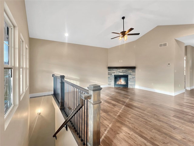 living room with a fireplace, light hardwood / wood-style flooring, vaulted ceiling, and ceiling fan