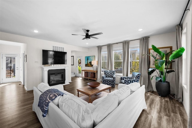 living room with visible vents, recessed lighting, wood finished floors, a ceiling fan, and a glass covered fireplace