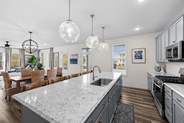 kitchen with a sink, gray cabinetry, a center island with sink, decorative light fixtures, and stainless steel appliances