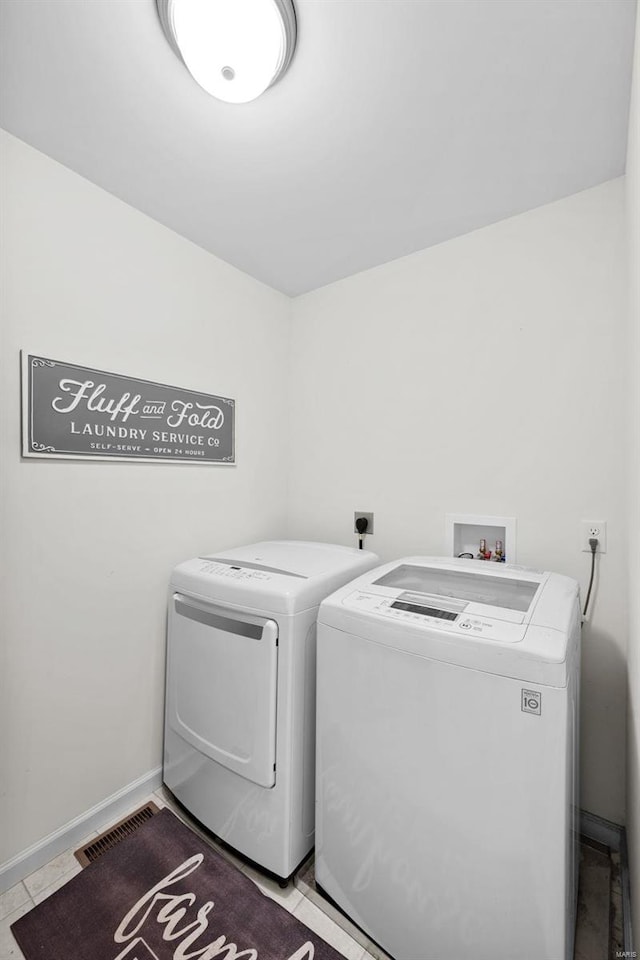 clothes washing area featuring washing machine and clothes dryer, visible vents, laundry area, and baseboards