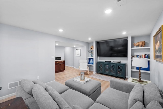 living room with baseboards, visible vents, recessed lighting, and light wood-style floors