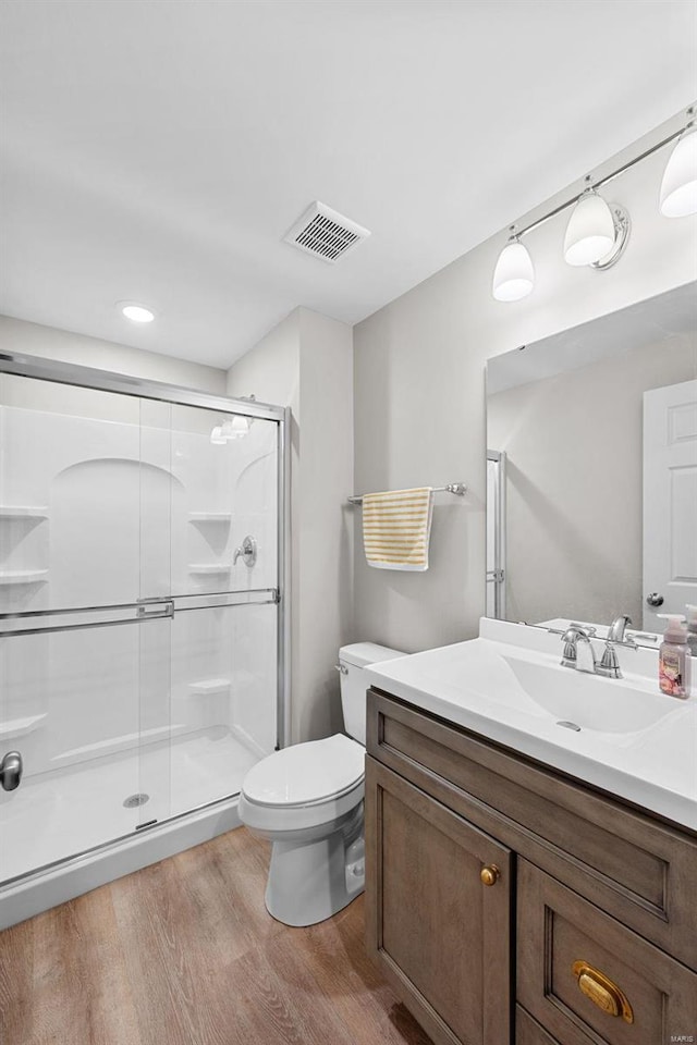 full bathroom featuring wood finished floors, a stall shower, vanity, visible vents, and toilet