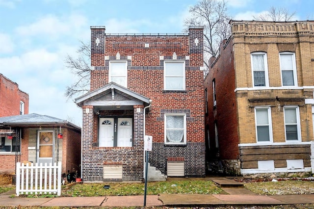 view of front of home featuring brick siding and fence