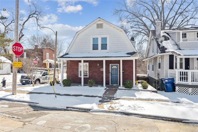 dutch colonial featuring brick siding and a gambrel roof