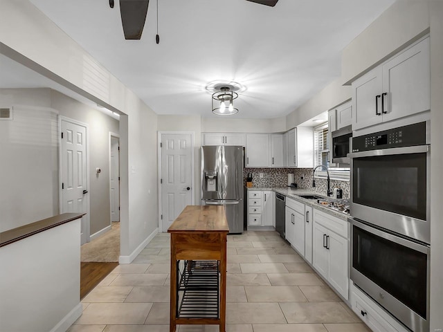 kitchen featuring decorative backsplash, white cabinets, appliances with stainless steel finishes, and a sink