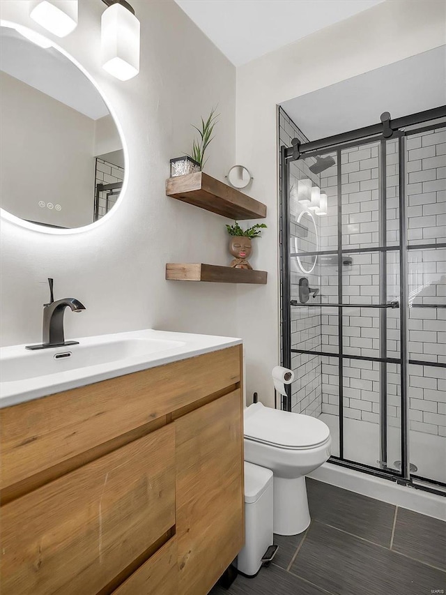 bathroom featuring vanity, a shower stall, toilet, and tile patterned flooring