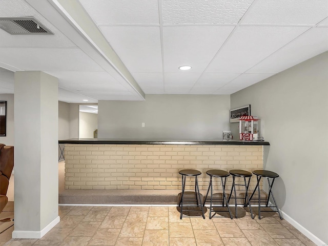 bar featuring visible vents, a bar, baseboards, and a drop ceiling