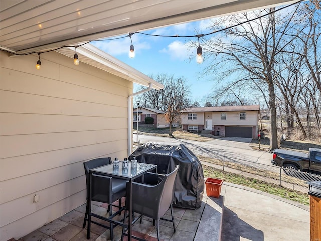 view of patio with outdoor dining space, a grill, driveway, and fence