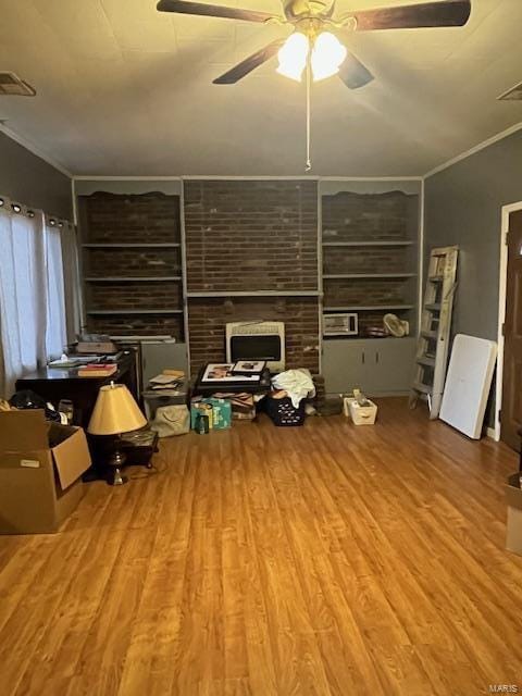 living room featuring built in shelves, wood-type flooring, ornamental molding, and ceiling fan