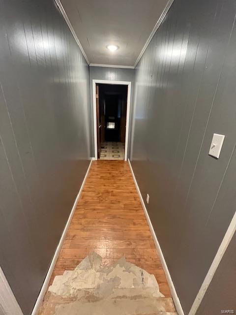 hall with crown molding, wood-type flooring, and wood walls