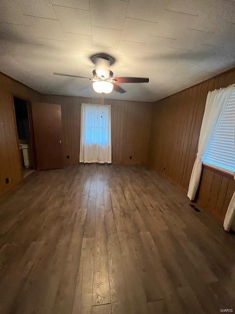 spare room with wood-type flooring, wooden walls, and ceiling fan