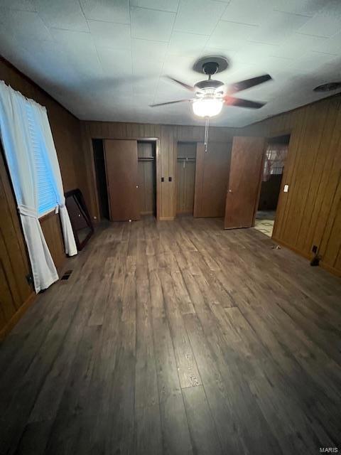 interior space with hardwood / wood-style flooring, ceiling fan, and wood walls