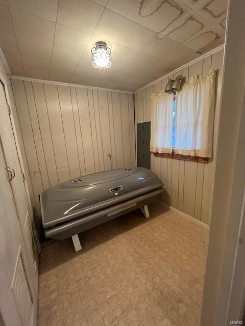 interior space featuring ornamental molding, electric panel, and wood walls