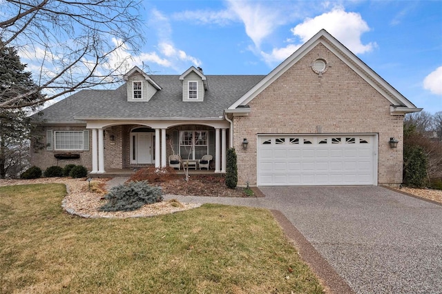 view of front of home featuring covered porch, aphalt driveway, a front lawn, and brick siding