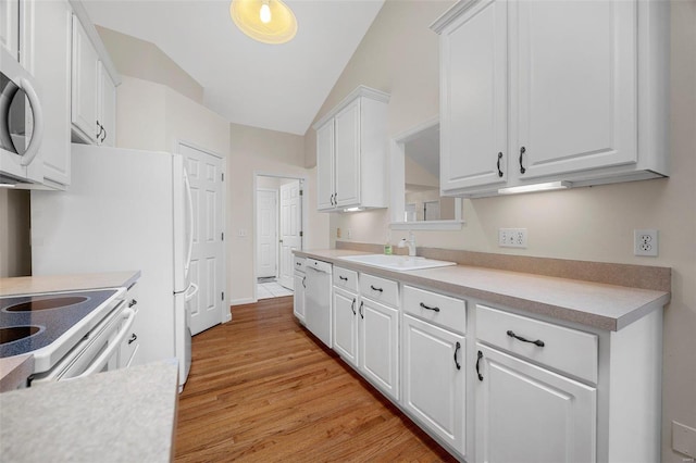 kitchen with stainless steel microwave, white dishwasher, light countertops, white cabinetry, and a sink