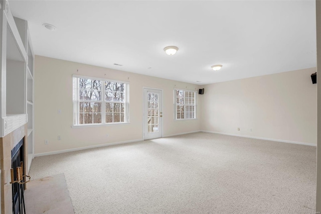 unfurnished living room with light carpet, a fireplace, baseboards, and a healthy amount of sunlight