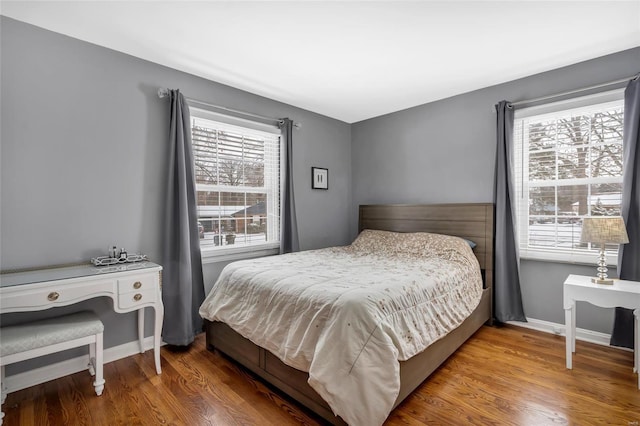 bedroom featuring wood finished floors, baseboards, and multiple windows