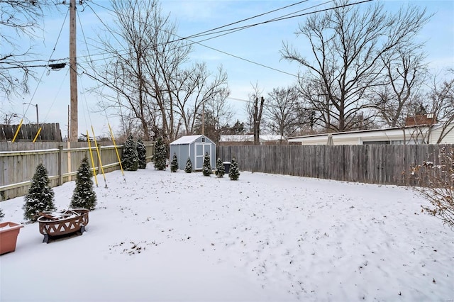 yard covered in snow featuring a storage shed, an outdoor structure, and a fenced backyard