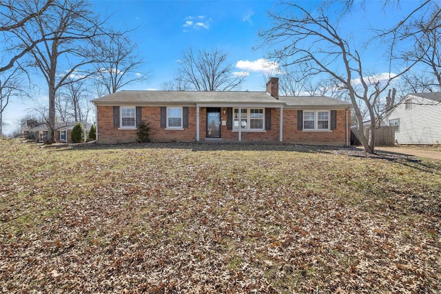 ranch-style house featuring brick siding, fence, a chimney, and a front lawn