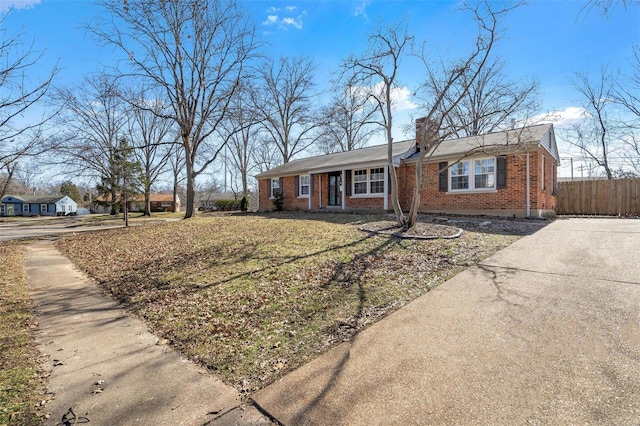 single story home with brick siding, a chimney, a front lawn, and fence