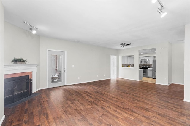 unfurnished living room with a fireplace, ceiling fan, dark hardwood / wood-style flooring, and rail lighting